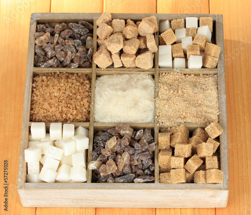 Different types of sugar in wooden box on table close-up