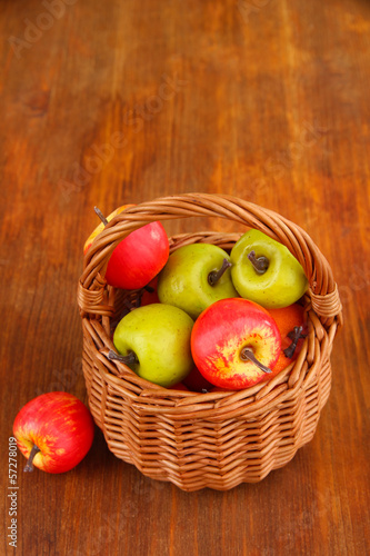Small apples in wicker basket on wooden background