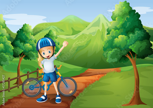 A cute little girl and her bike at the pathway near the wooden f