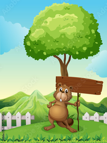 A beaver under the tree with an empty wooden board
