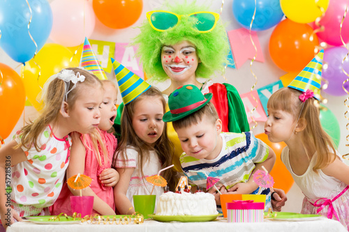 kids with clown celebrating birthday party and blowing candles o