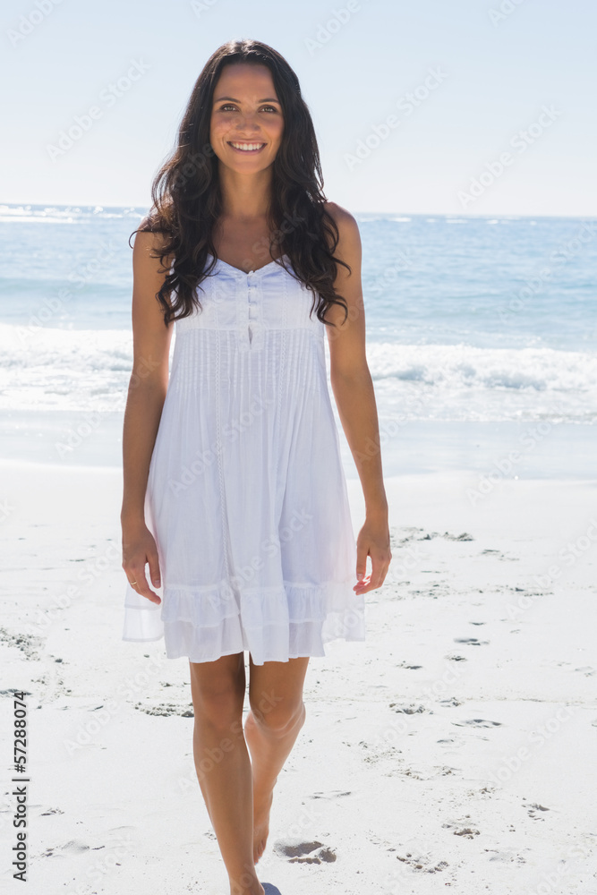Smiling brunette in white sun dress walking towards camera Smiling brunette in white sun dress walking towards camera