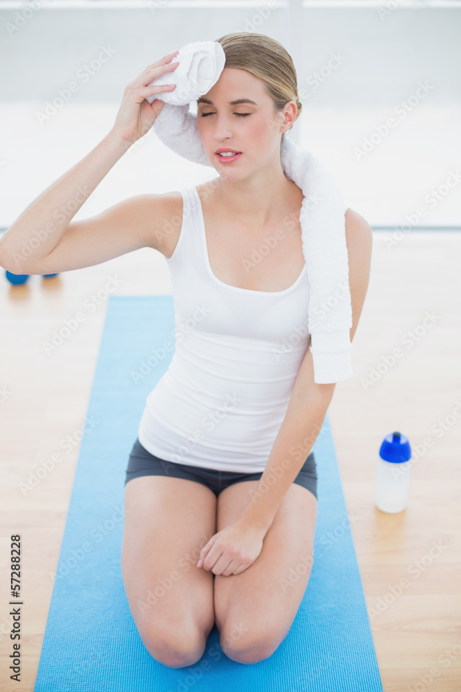 Exhausted fit woman on her knees wiping her forehead Exhausted fit woman on her knees wiping her forehead