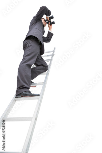 Low angle view of businessman standing on ladder using binocular