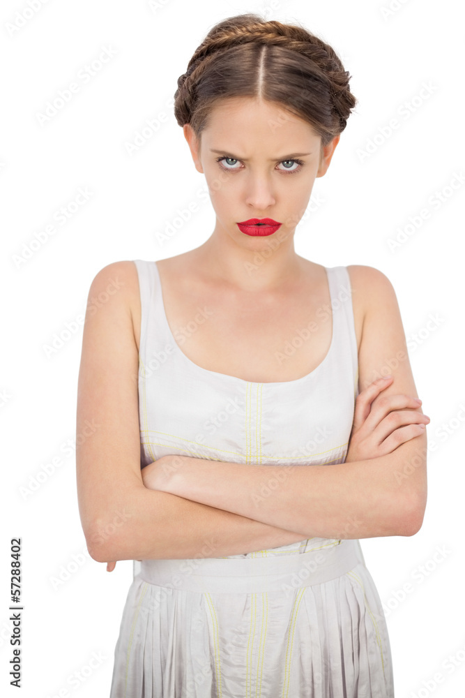 Frowning model in white dress posing with crossed arms Frowning model in white dress posing with crossed arms