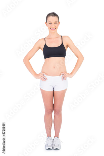 Smiling woman in sportswear hands on hips looking at camera