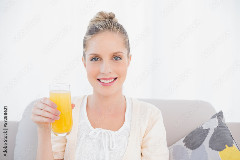 Gorgeous model holding orange juice sitting on sofa Gorgeous model holding orange juice sitting on sofa