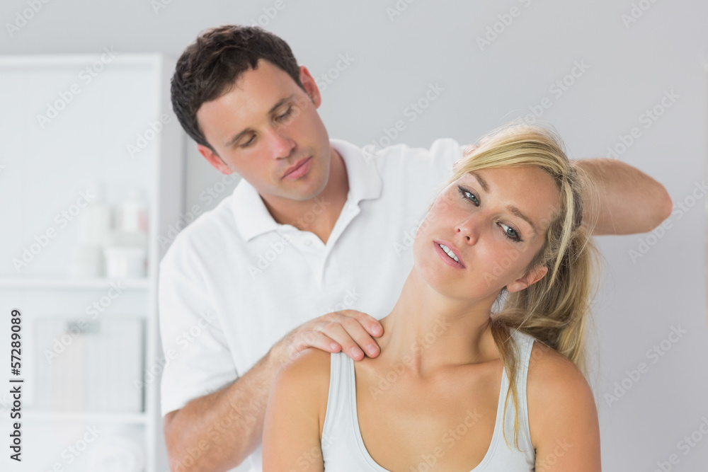 Handsome physiotherapist examining patients neck Handsome physiotherapist examining patients neck