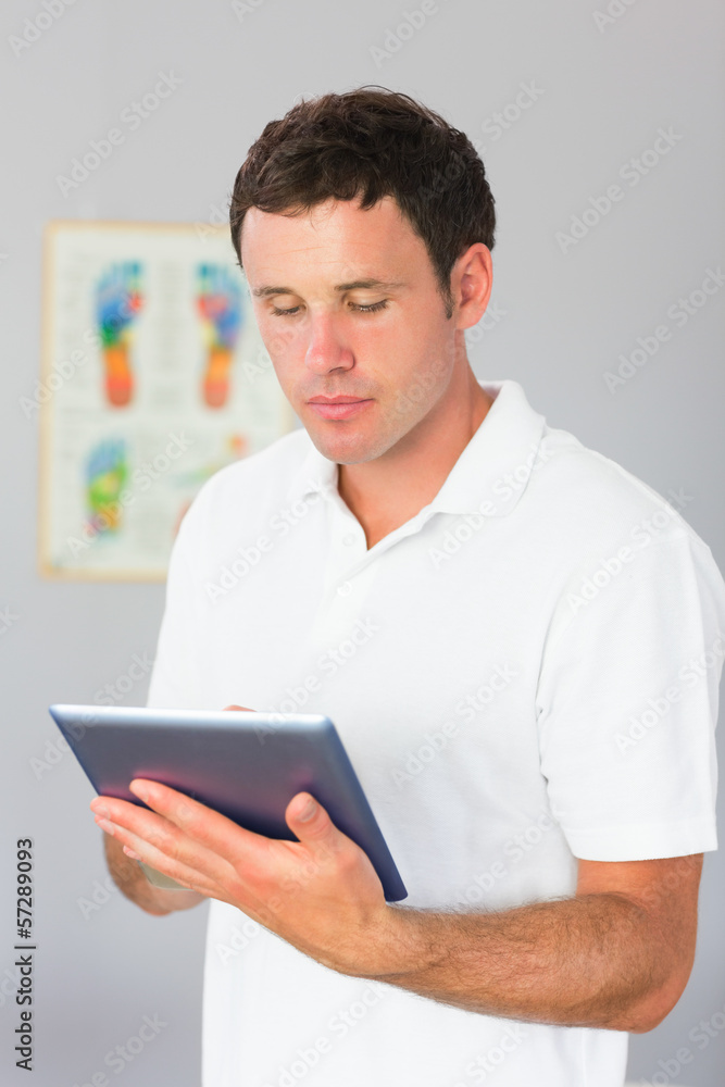 Handsome physiotherapist using tablet Handsome physiotherapist using tablet
