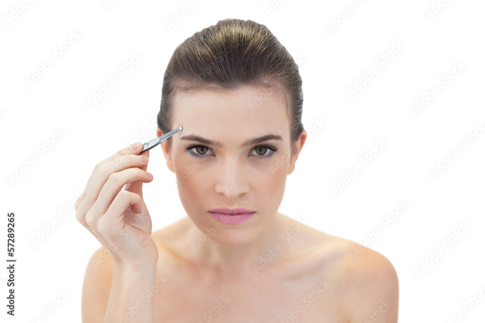 Serious natural brown haired model plucking her eyebrows Serious natural brown haired model plucking her eyebrows