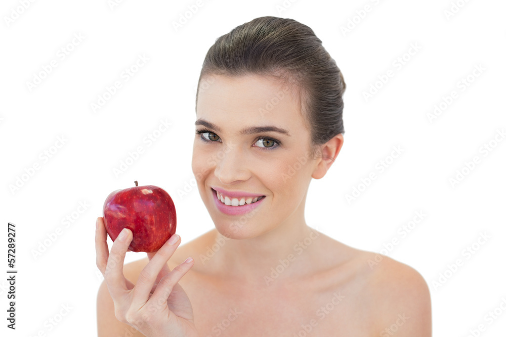 Relaxed natural brown haired model holding a red apple Relaxed natural brown haired model holding a red apple