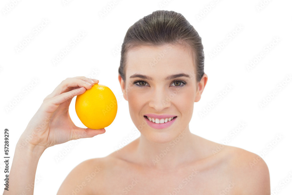 Laughing natural brown haired model holding an orange Laughing natural brown haired model holding an orange