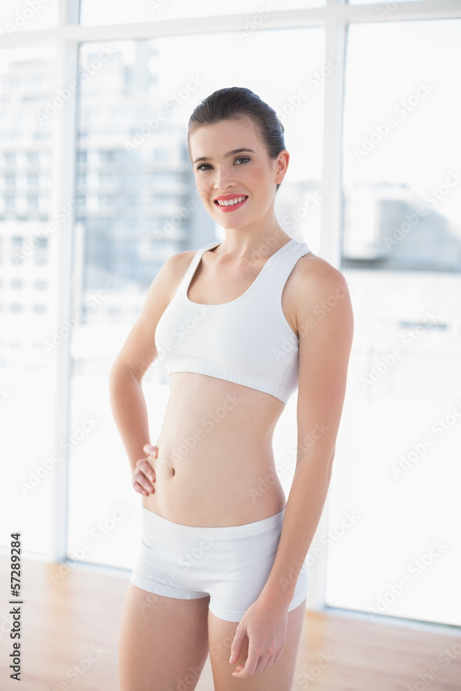 Content fit brown haired model in sportswear posing with a hand