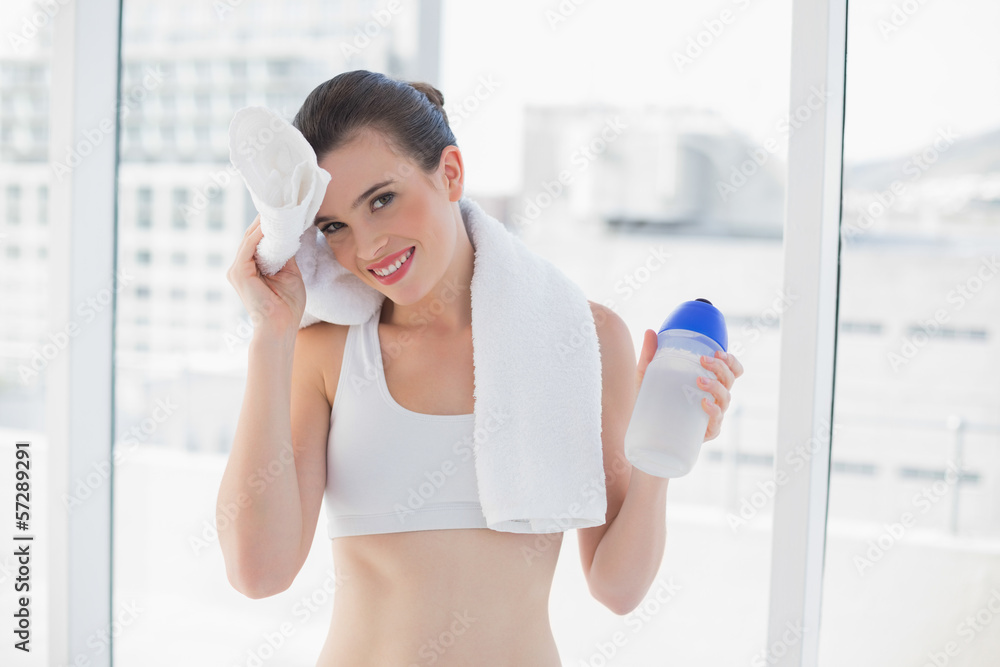 Tired fit brown haired model in sportswear wiping her brow with Tired fit brown haired model in sportswear wiping her brow with