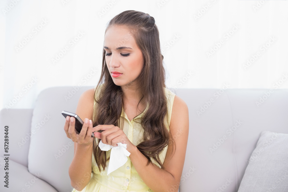 Upset young brunette holding mobile phone and tissue Upset young brunette holding mobile phone and tissue
