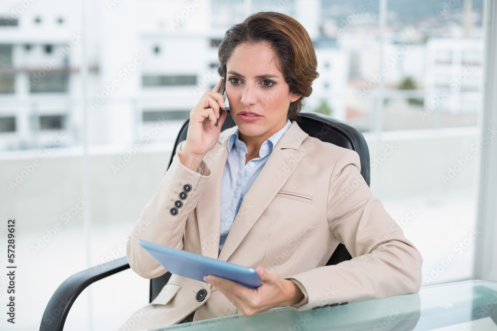Frowning businesswoman on a call holding tablet Frowning businesswoman on a call holding tablet