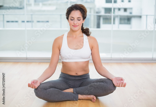 Sporty content brunette sitting in lotus pose with eyes closed