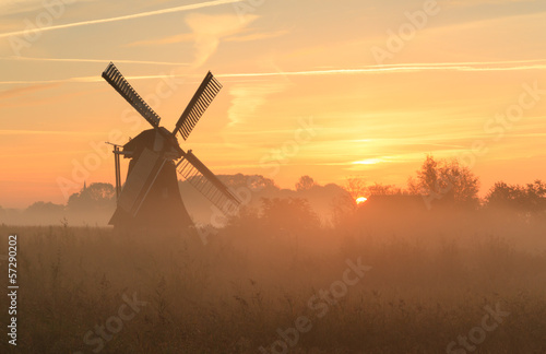 Windmill at foggy sunrise