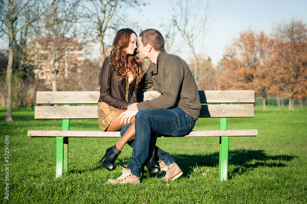 Happy young couple sitting outdoors on a bench. Happy young couple sitting outdoors on a bench.