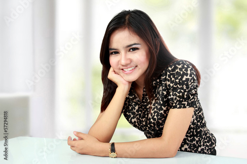 Smiling asian woman with hand on chin sitting Free Download Smiling asian woman with hand on chin sitting - GFXLoad