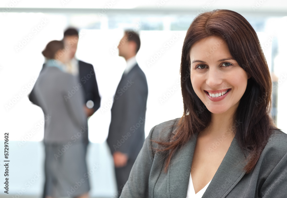 Happy businesswoman posing while her team discussing Happy businesswoman posing while her team discussing