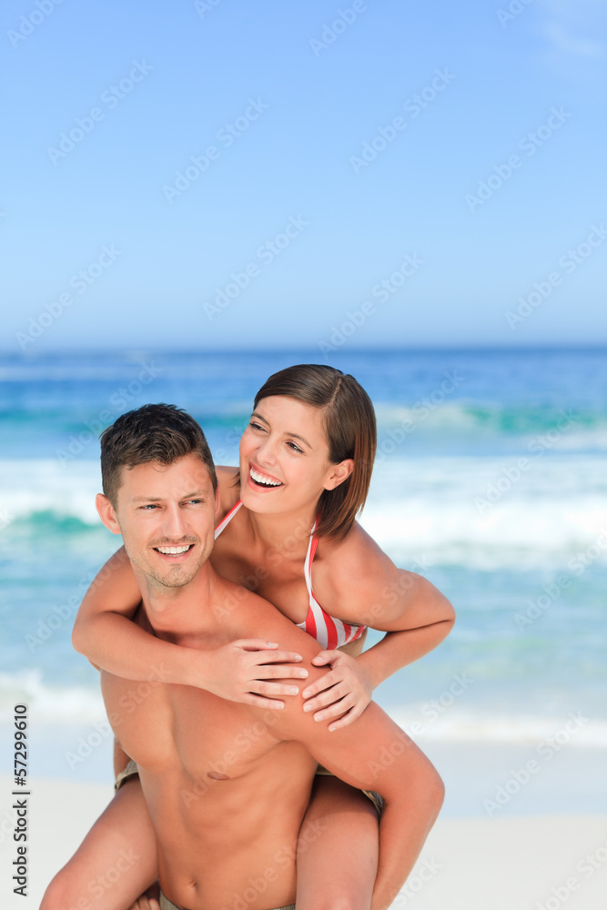 Handsome man having wife a piggyback on the beach Handsome man having wife a piggyback on the beach