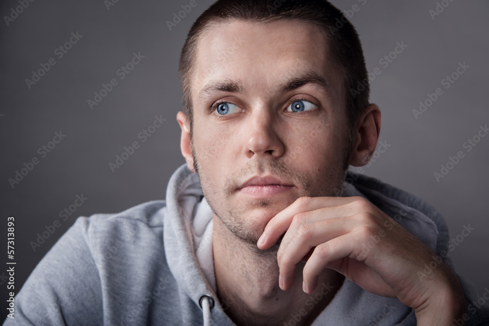 Closeup of young man with hand on head on gray background Closeup of young man with hand on head on gray background