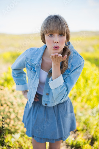 Trendy young woman sending kiss to camera