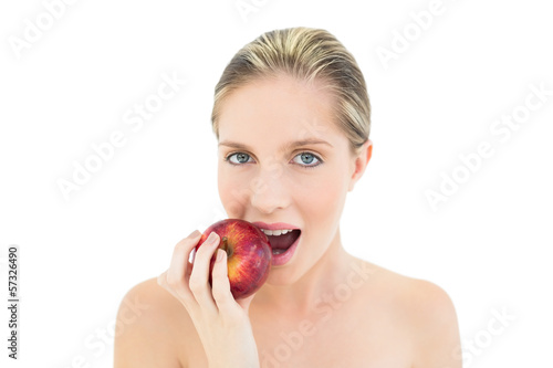 Beautiful fresh blonde woman eating a red apple