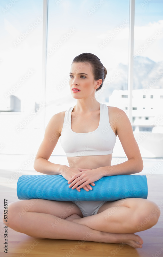 Thoughtful fit brown haired model in sportswear sitting and carr Thoughtful fit brown haired model in sportswear sitting and carr