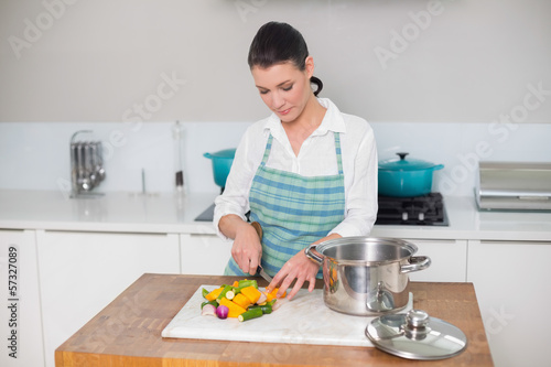 Focused pretty woman chopping vegetables