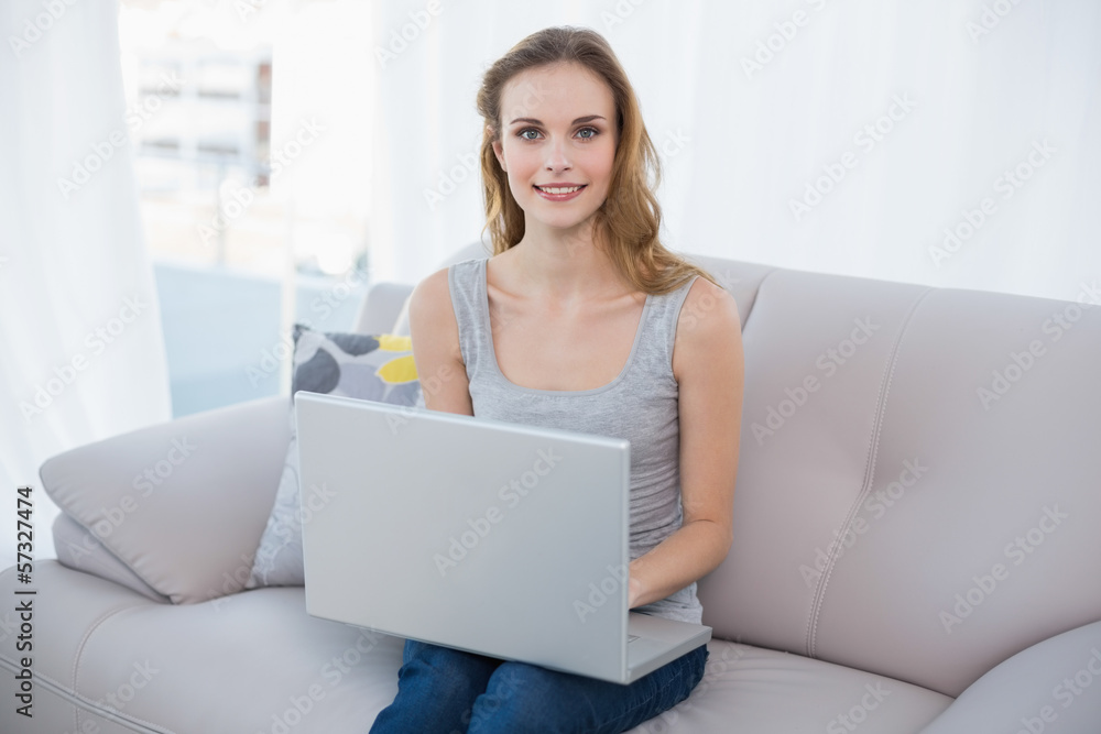 Happy young woman sitting on couch using laptop Happy young woman sitting on couch using laptop