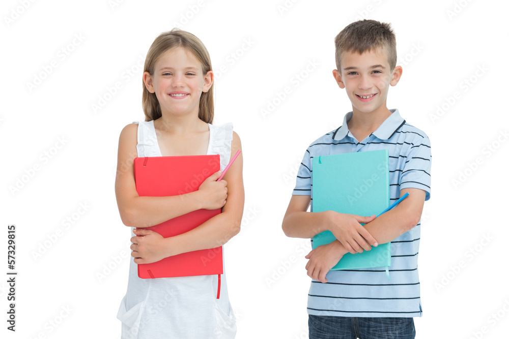 Cheerful brother and sister holding their exercise books Cheerful brother and sister holding their exercise books