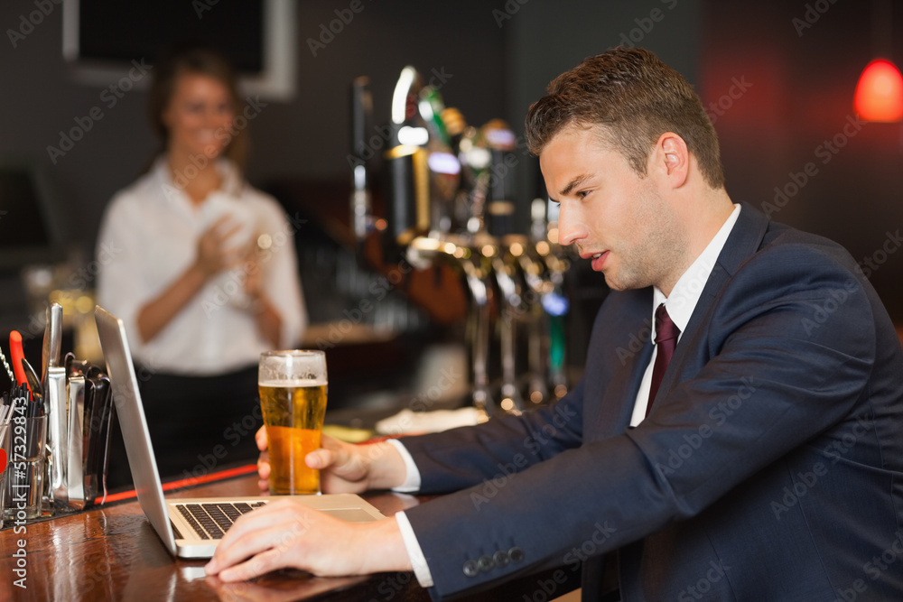 Businessman having a beer while working on his laptop