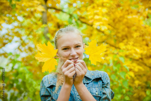 Young woman with autumn leaves near her face