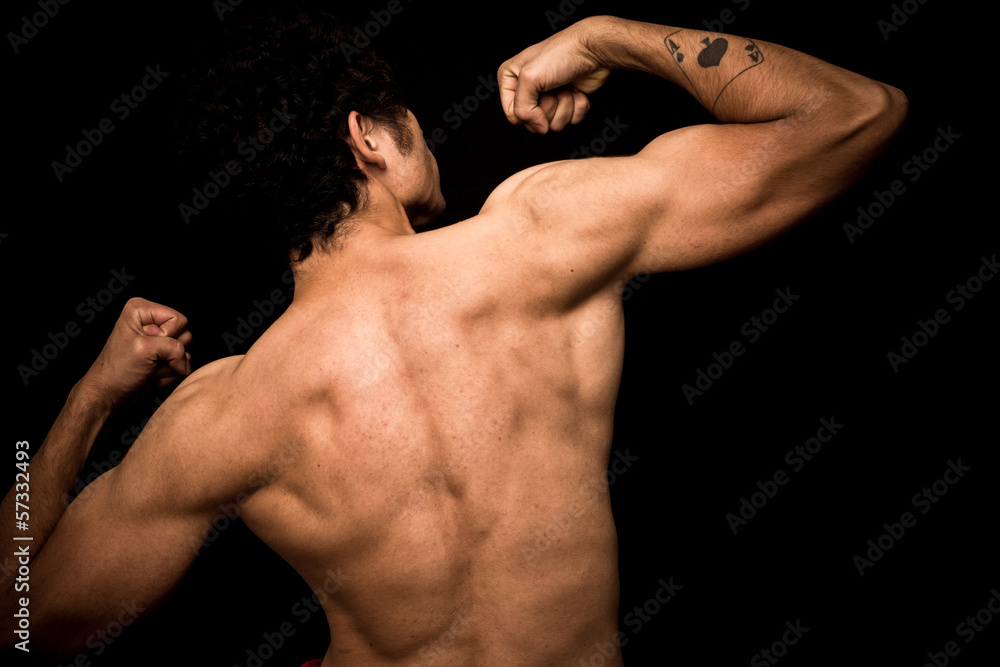 Young athletic shirtless man posing on black background