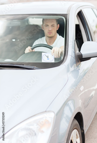 man placing parking clock on car dashboard