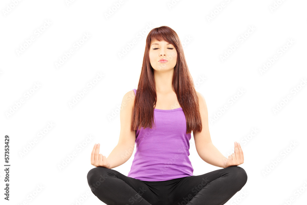 Young female athlete in outfit sitting on a floor and meditating Young female athlete in outfit sitting on a floor and meditating