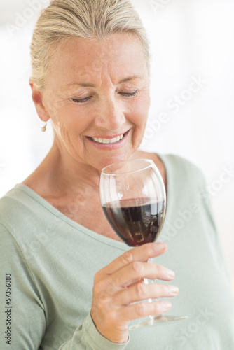 Woman Smelling Red Wine At Home