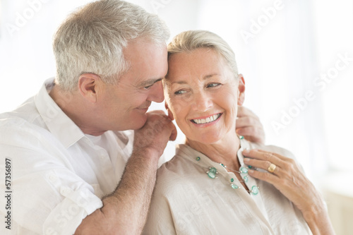 Man Putting Necklace Around Woman's Neck At Home