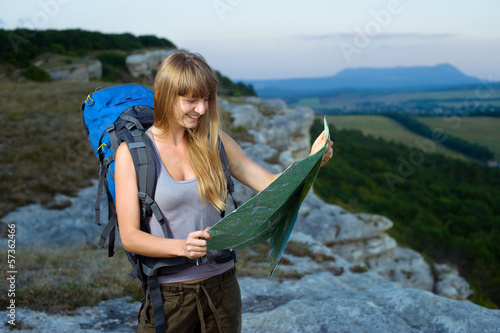 Girl standing at the edge of mountain and looking at map photo