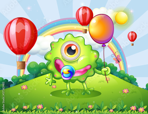 A baby green monster at the hilltop with a rainbow