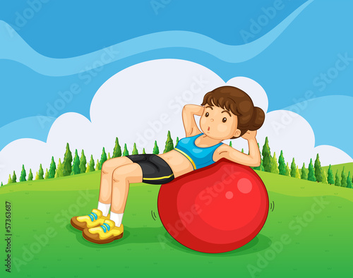 A young lady exercising with a bouncing ball in the hill