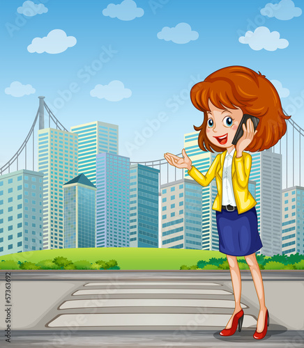 A lady with a cellphone standing at the pedestrian lane