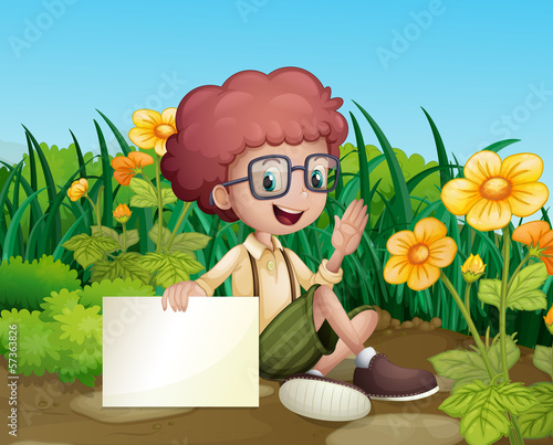 A smiling young boy near the flowers holding an empty signboard