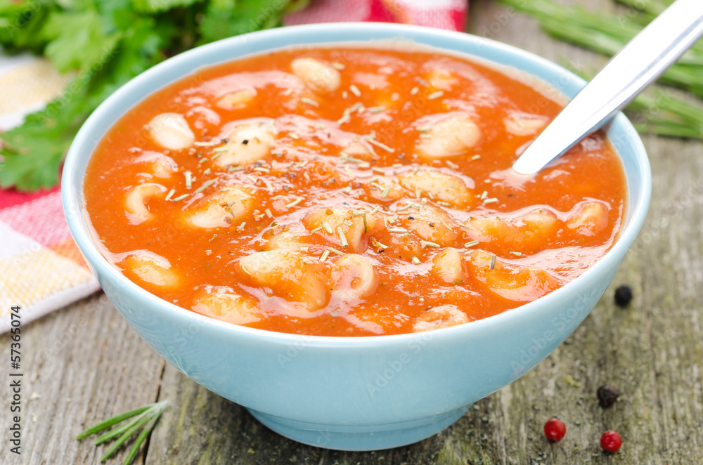 tomato soup with pasta, beans and rosemary in a blue bowl tomato soup with pasta, beans and rosemary in a blue bowl