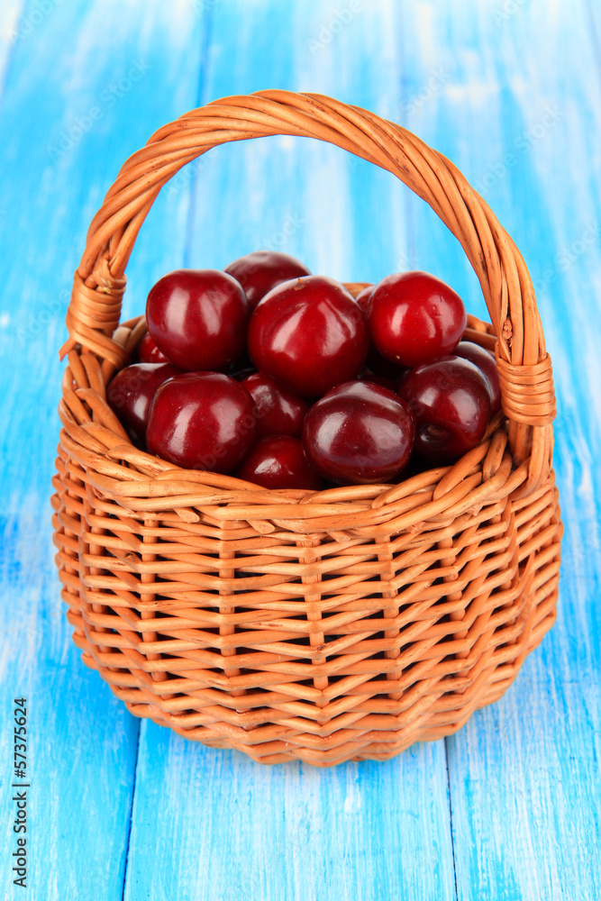 Cherry berries in wicker basket on wooden table close-up Cherry berries in wicker basket on wooden table close-up