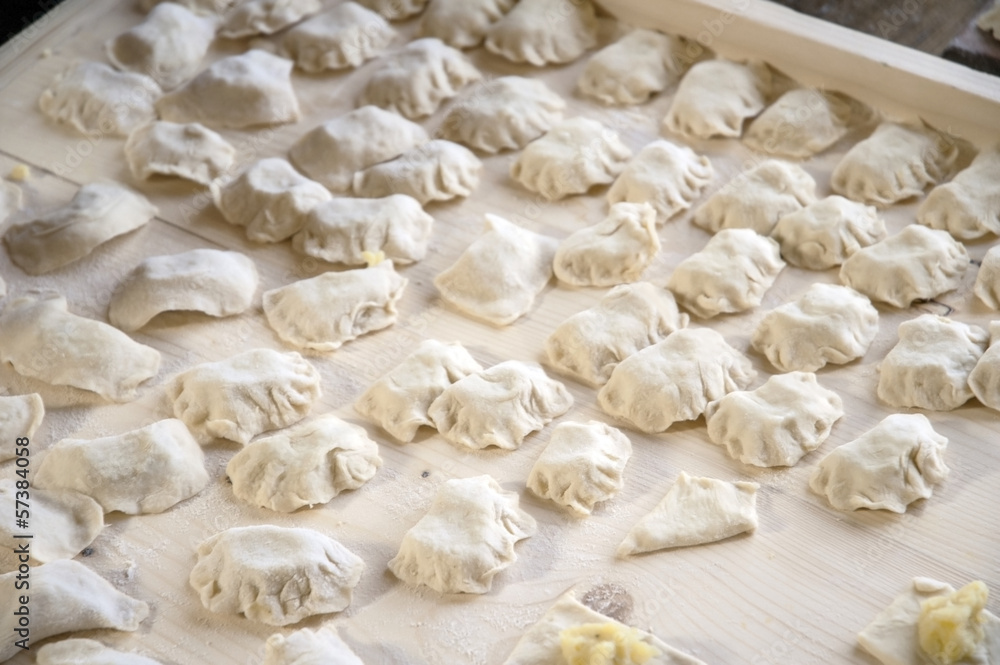 Raw dumplings with potato on carving board. Raw dumplings with potato on carving board.