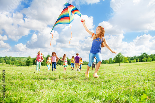 Girl running with kite with friends