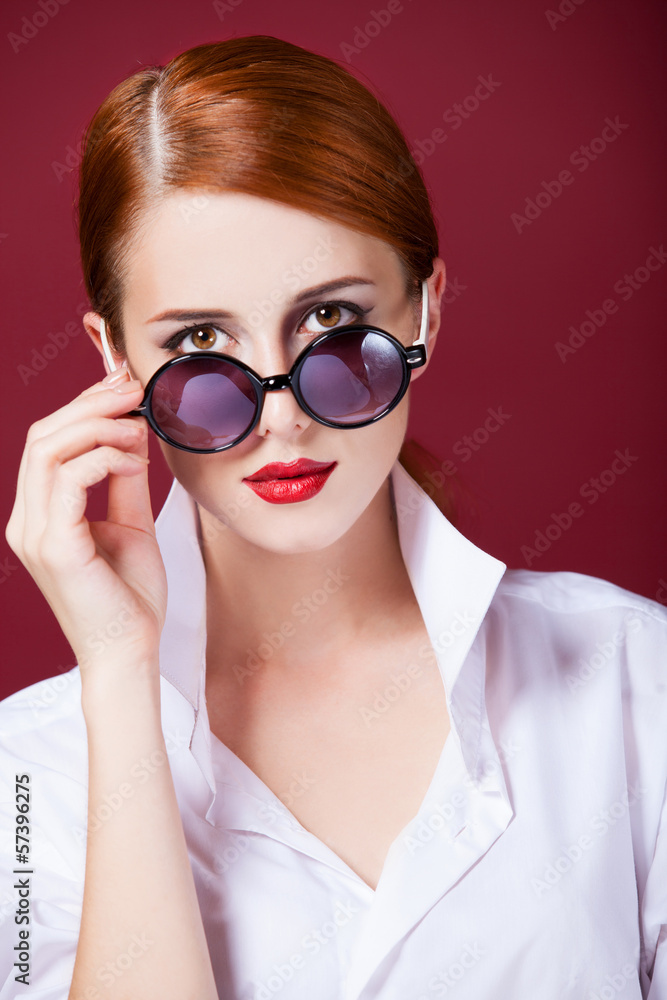 Redhead in sunglasses on red background Redhead in sunglasses on red background